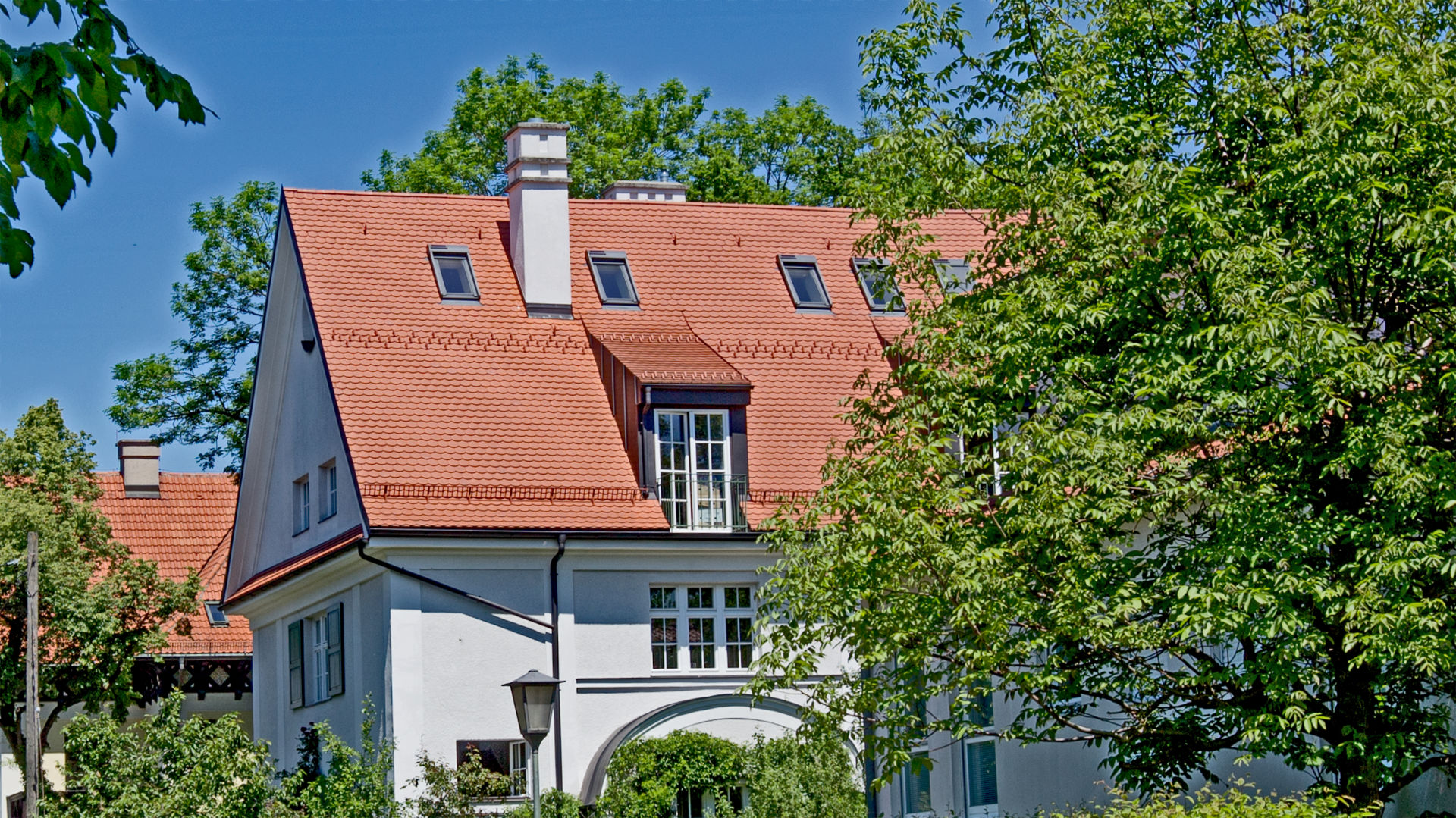 Weißes Haus mit rotem Ziegeldach und grünem Garten im Münchner Stadtteil Laim