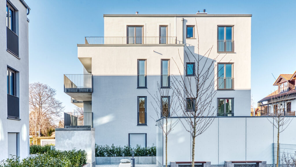 Modernes weißes Mehrfamilienhaus mit Balkonen und großen Fensterfronten