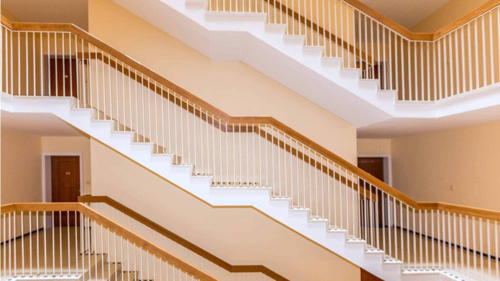 Elegantes Treppenhaus mit mehreren geschwungenen Treppenläufen und hellem Geländer