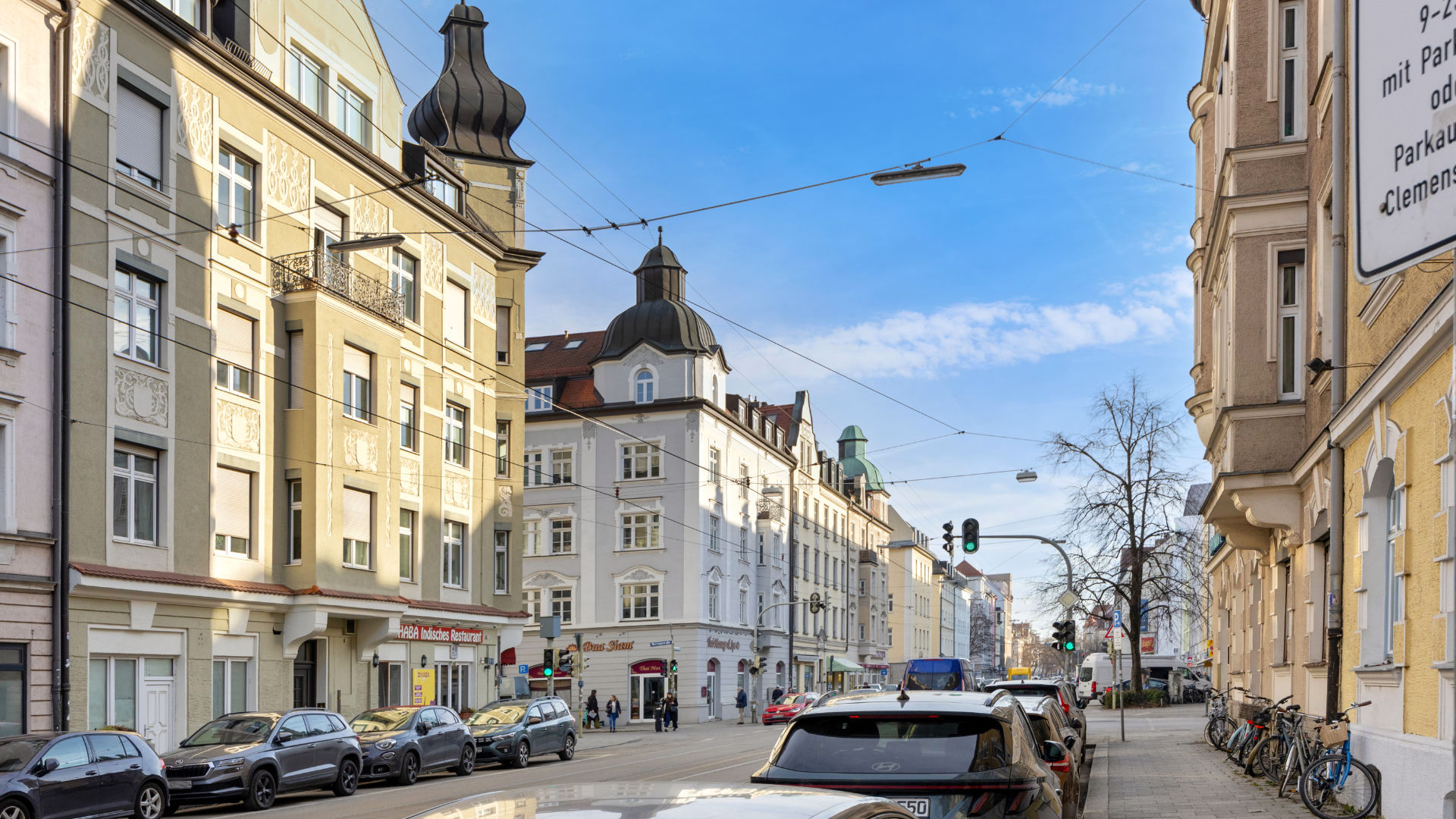 Belebte Wohnstraße mit Altbaufassaden, parkenden Autos und Fahrrädern im Münchner Stadtteil Schwabing