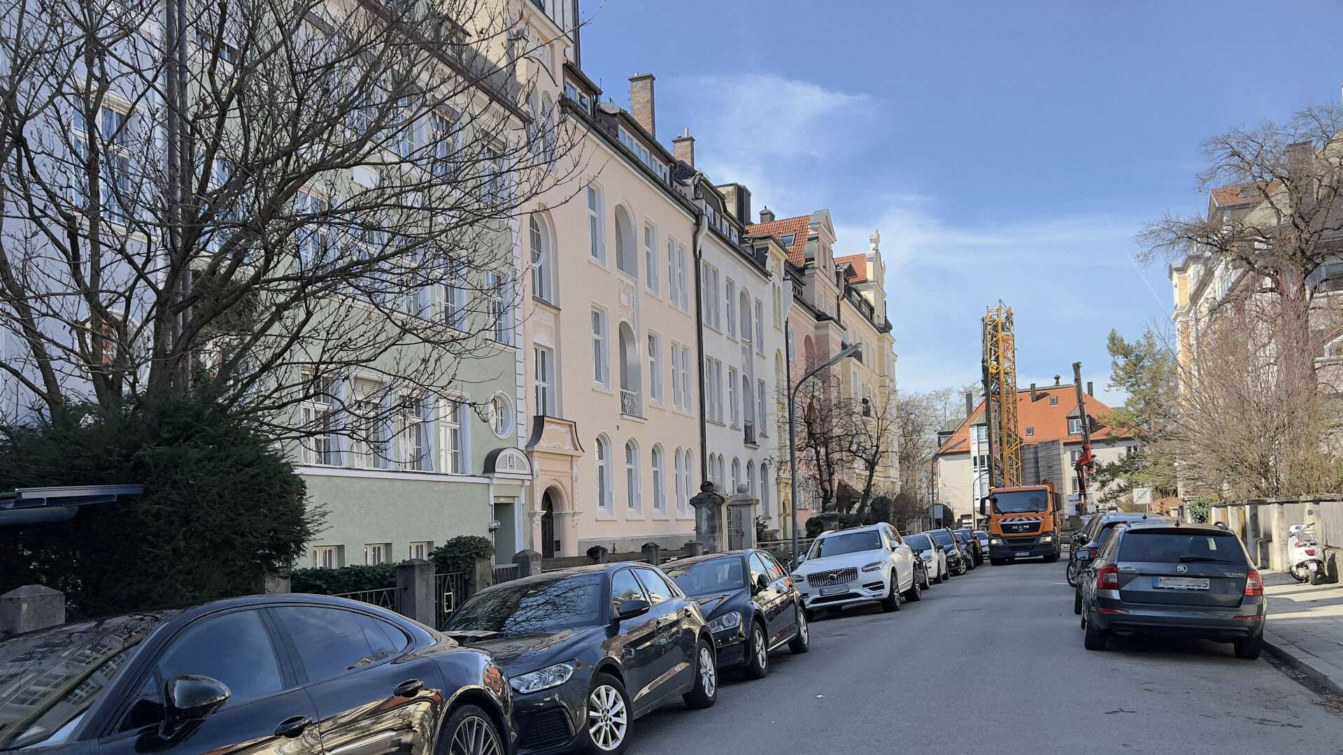 Altbaustraße mit parkenden Autos und Kirchturmblick im Münchner Stadtteil Au