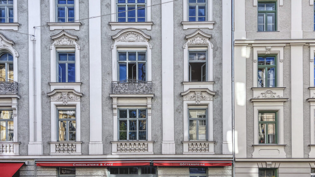 Historische Fassade mit hohen Fenstern und rotem Markisendach über einem Ladengeschäft