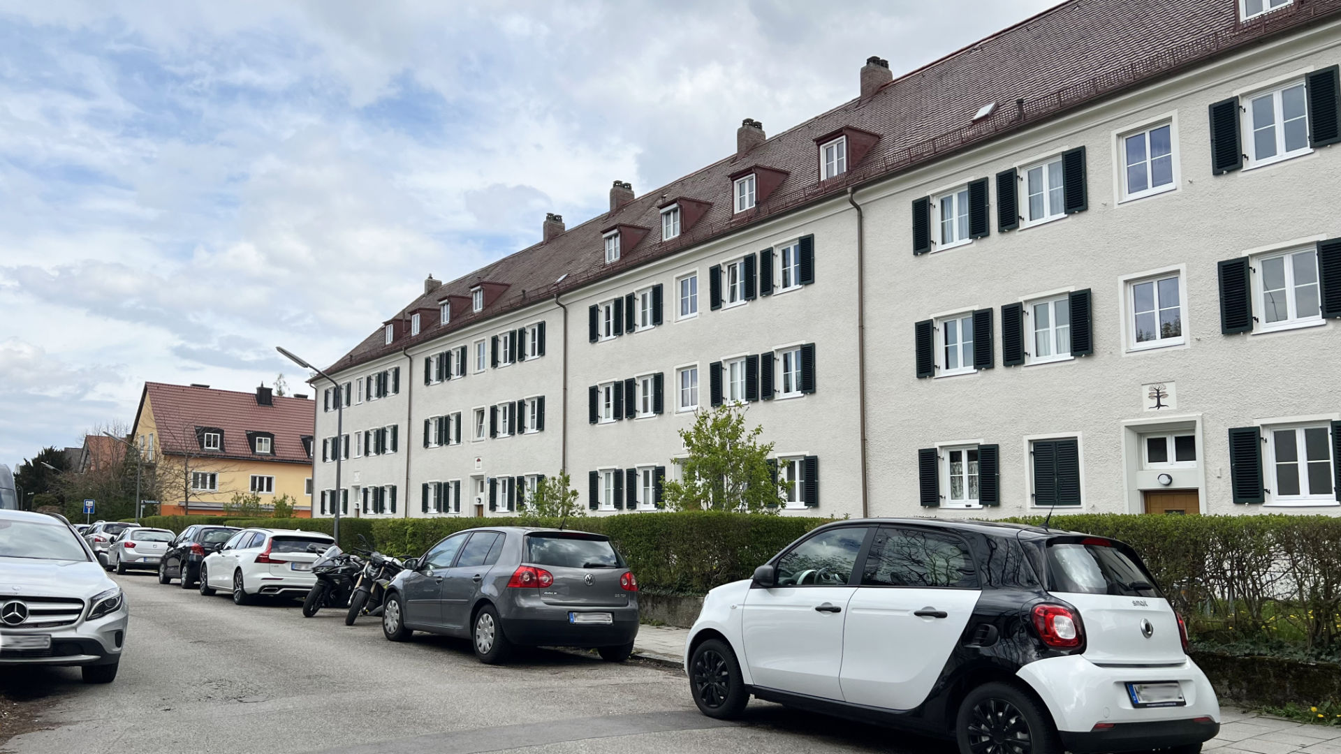 Wohnhauszeile mit dunklen Fensterläden und parkenden Autos im Münchner Stadtteil Laim