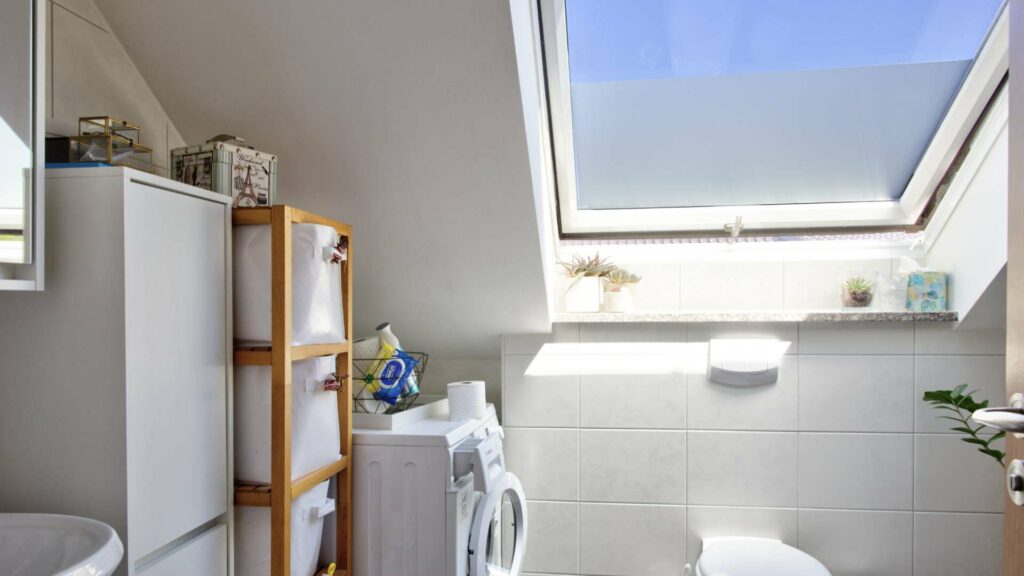 Kleines Badezimmer mit Dachfenster, Waschmaschine und WC unter der Dachschräge in einer Wohnung in Aubing
