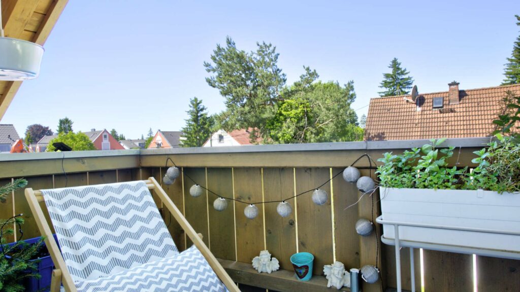 Balkon der Wohnung in Aubing mit Liegestuhl, Lichterkette und Blick über Dächer