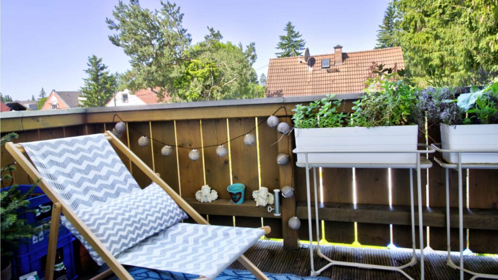 Balkon mit Liegestuhl und bepflanzten Kästen mit Blick auf Nachbardächer in Aubing