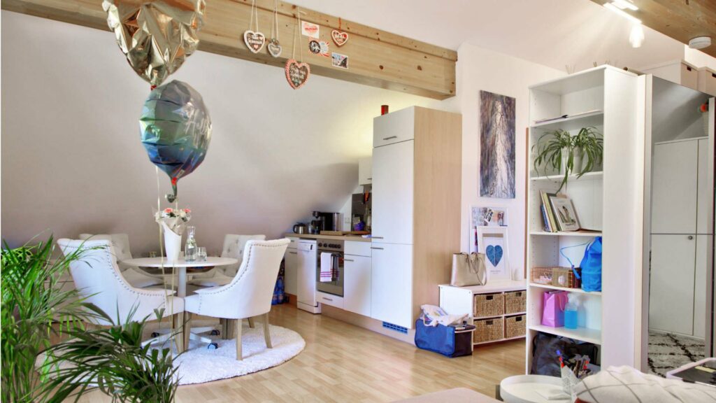 Wohn-Essbereich mit Küchenzeile, Esstisch und Balkonballon in einer Dachgeschosswohnung in Aubing