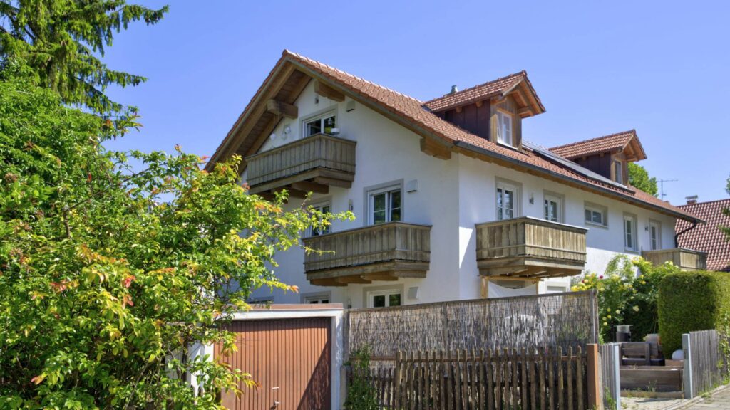 Wohnhaus mit hölzernen Balkonen und rotem Ziegeldach im bayerischen Stil in Aubing München