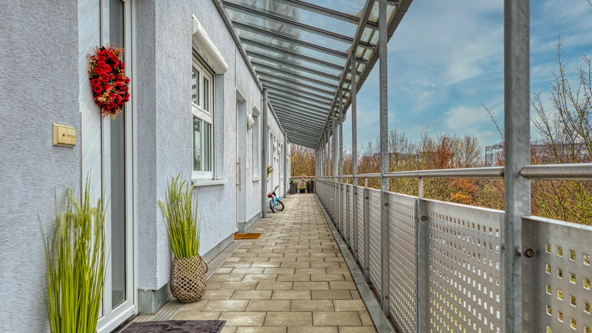 Überdachter Balkongang mit Glasdach entlang einer Hausfassade