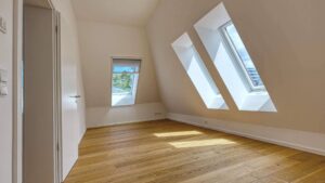 Leeres Zimmer im Dachgeschoss mit zwei Dachflächenfenstern und Parkettboden in einer Doppelhaushälfte in Bogenhausen