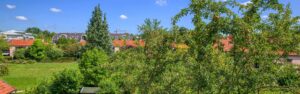 Blick über Gartengrün und Nachbarhäuser mit roten Dächern vom Obergeschoss einer Doppelhaushälfte in Bogenhausen