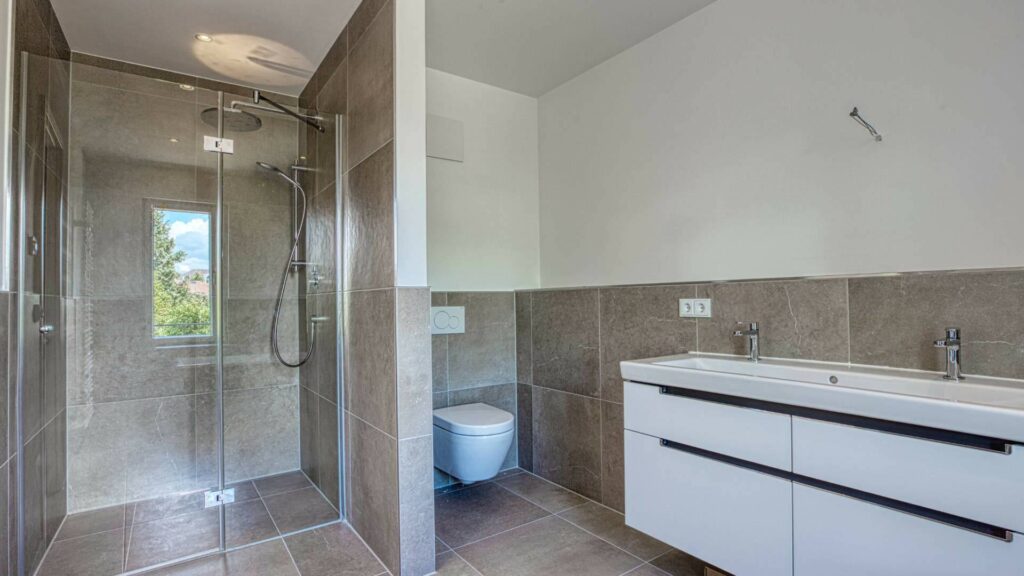 Modernes Badezimmer mit Glasdusche, WC und Doppelwaschtisch im Obergeschoss einer Doppelhaushälfte in Bogenhausen
