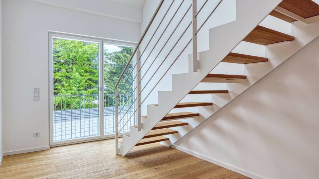 Moderne offene Treppe mit Edelstahlgeländer neben einer Terrassentür in einer Doppelhaushälfte in Bogenhausen