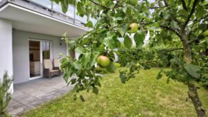 Gepflasterte Terrasse mit Sitzgelegenheit unter einem Apfelbaum hinter einer Wohnung in Bogenhausen