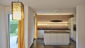 Moderne offene Küche mit Kochinsel, Holzfront und dunklem Boden in einer Wohnung in Bogenhausen