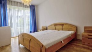 Schlafzimmer mit Holzbett, blauen Vorhängen und Balkonzugang in einer Wohnung in Bogenhausen