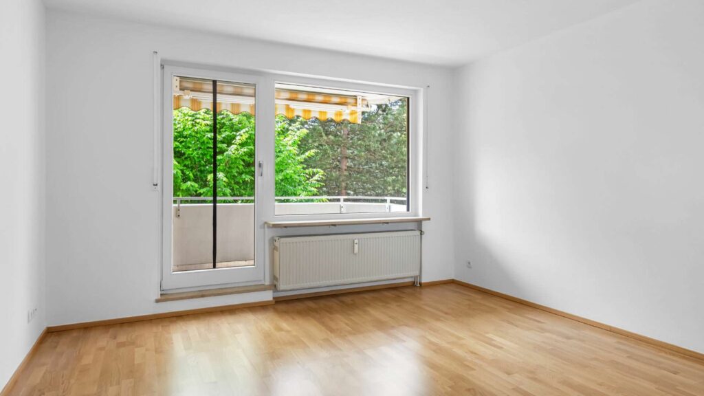 Empty living room with a window and view of the balcony in an apartment in Bogenhausen