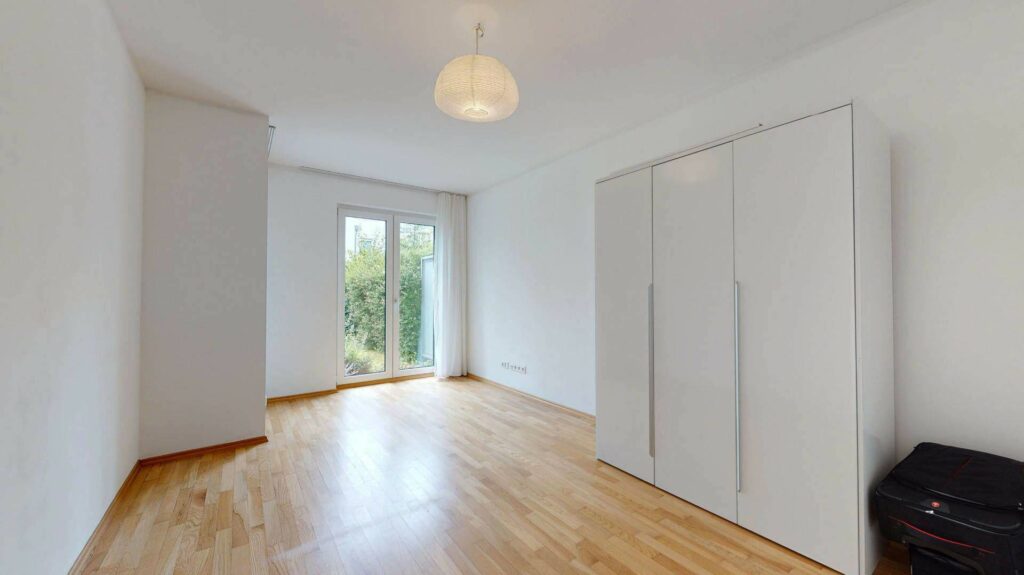 Unmöbliertes Zimmer mit Parkettboden, Einbauschrank und Terrassentür in einer Wohnung in Bogenhausen
