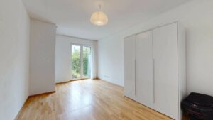 Unmöbliertes Zimmer mit Parkettboden, Einbauschrank und Terrassentür in einer Wohnung in Bogenhausen