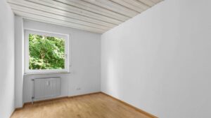 Empty room with slanted ceiling and wood paneling in an apartment in Bogenhausen