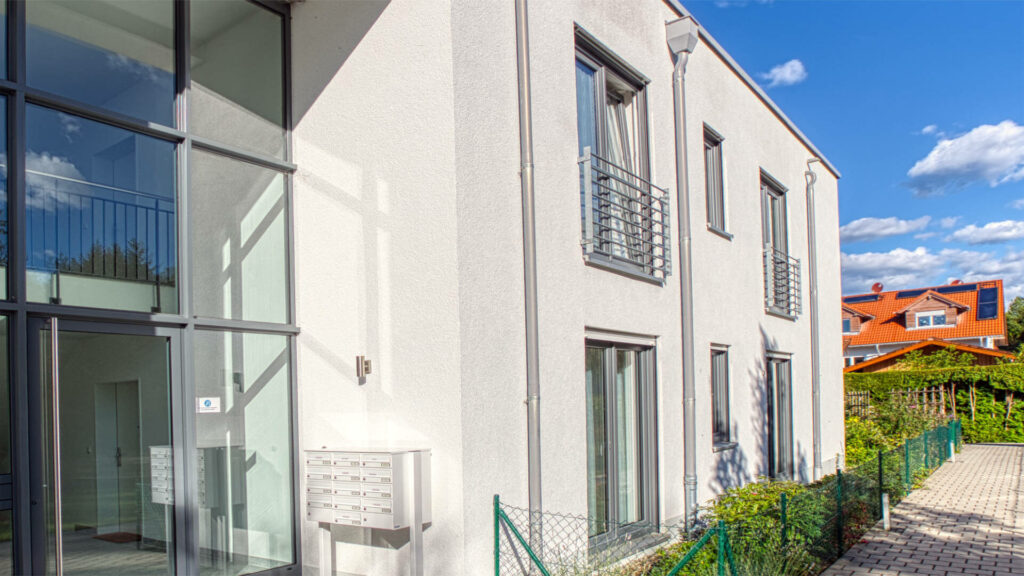 Weißes Neubau-Reihenhaus mit Balkonen und großen Fenstern
