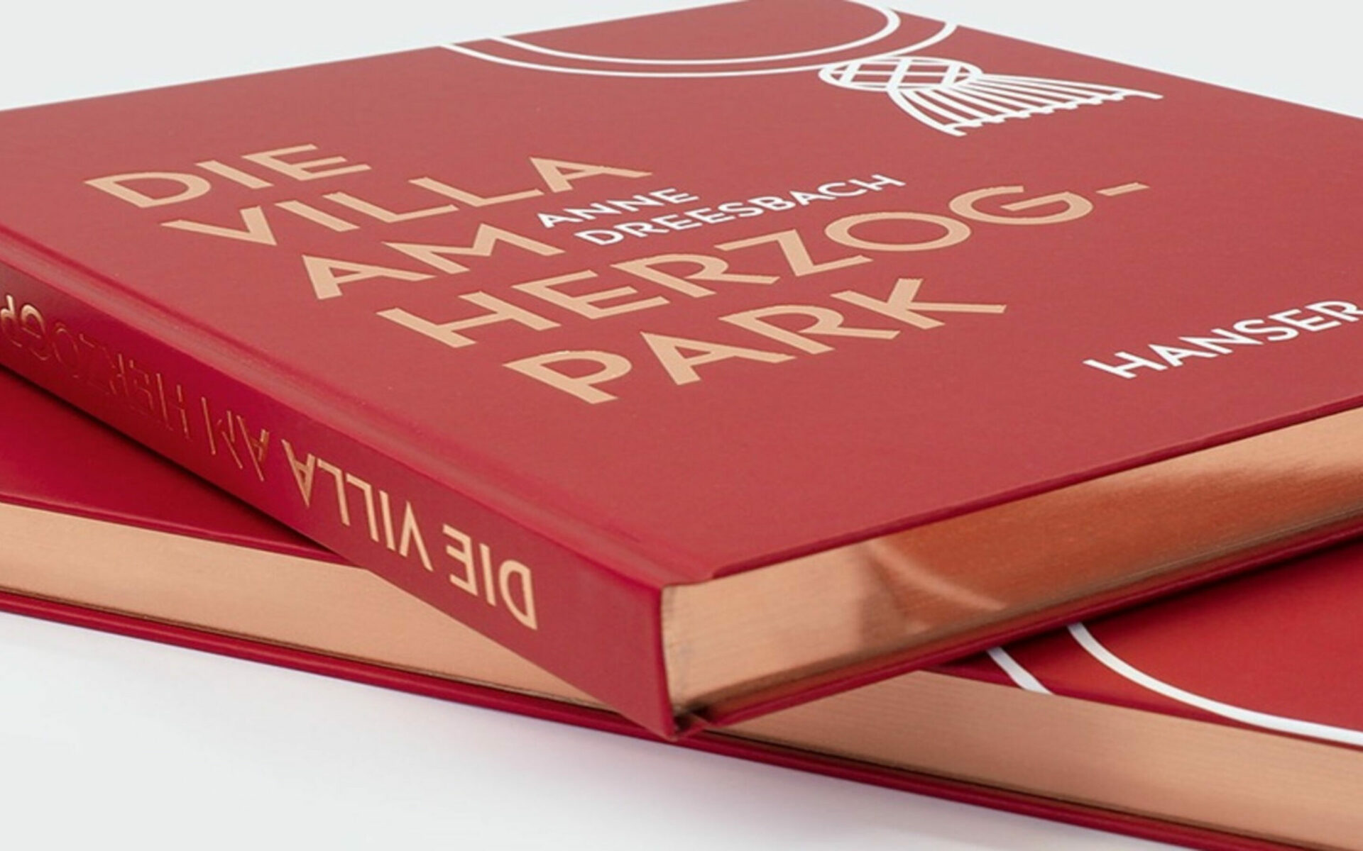 Zwei gestapelte Exemplare des Buches "Die Villa am Herzogpark" in Rot mit Goldschnitt