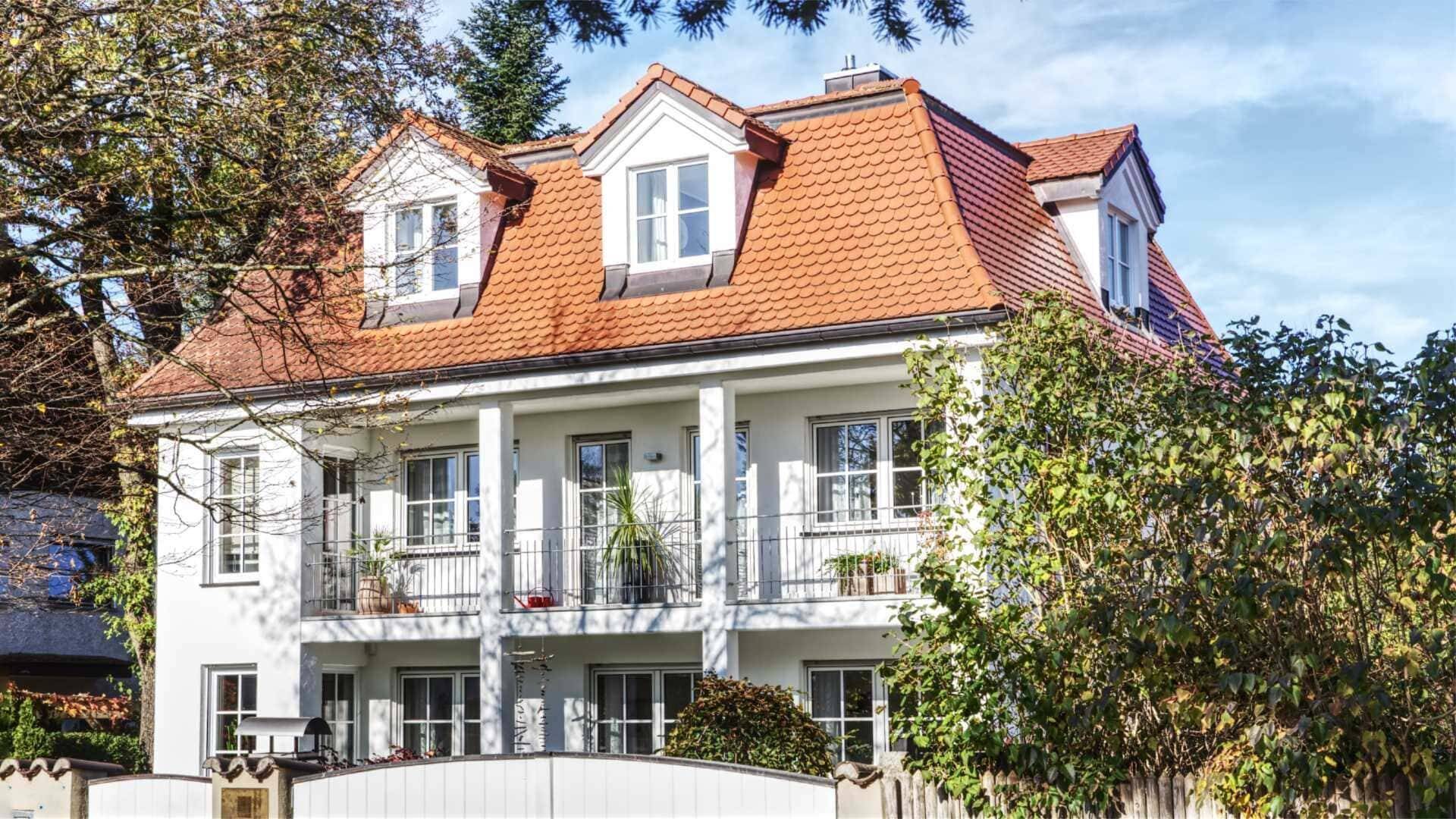 Weiße klassizistische Villa mit orangem Ziegeldach und Säulenbalkon