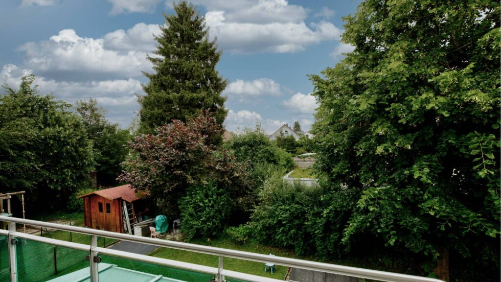 View from the glass balcony of the garden with a small garden house in Munich-Forstenried