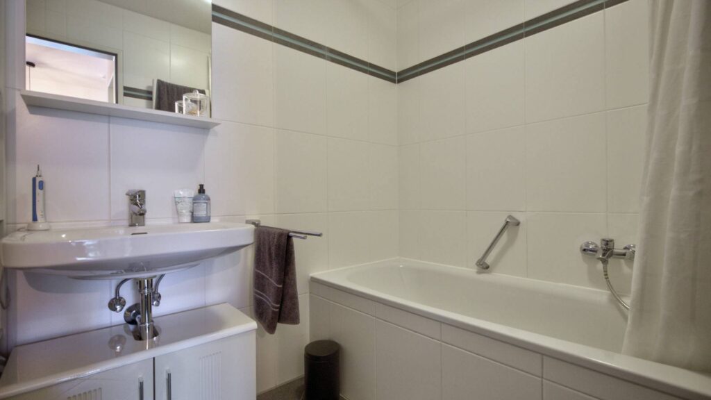 Bathroom with washbasin, wall shelf and bathtub in an apartment in Munich-Forstenried