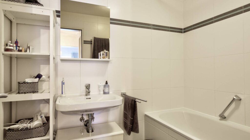 Bathroom of the apartment in Forstenried with shelf, sink, mirror, and bathtub