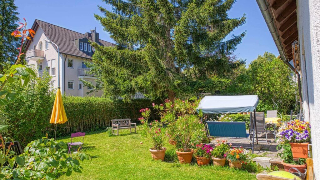 Gartenbereich des Grundstücks in Forstenried mit überdachtem Sitzplatz und Blumenkübeln