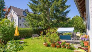 Gartenbereich des Grundstücks in Forstenried mit überdachtem Sitzplatz und Blumenkübeln