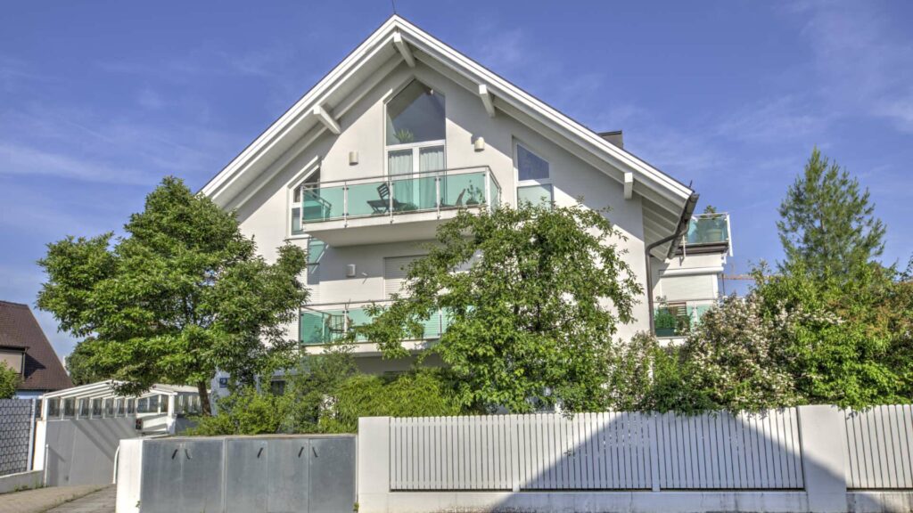 White apartment building with glass balconies and gable roof in Munich-Forstenried