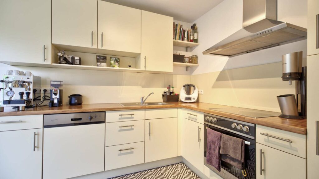 Fitted kitchen with white cabinets, wooden countertop and extractor hood in an apartment in Munich-Forstenried
