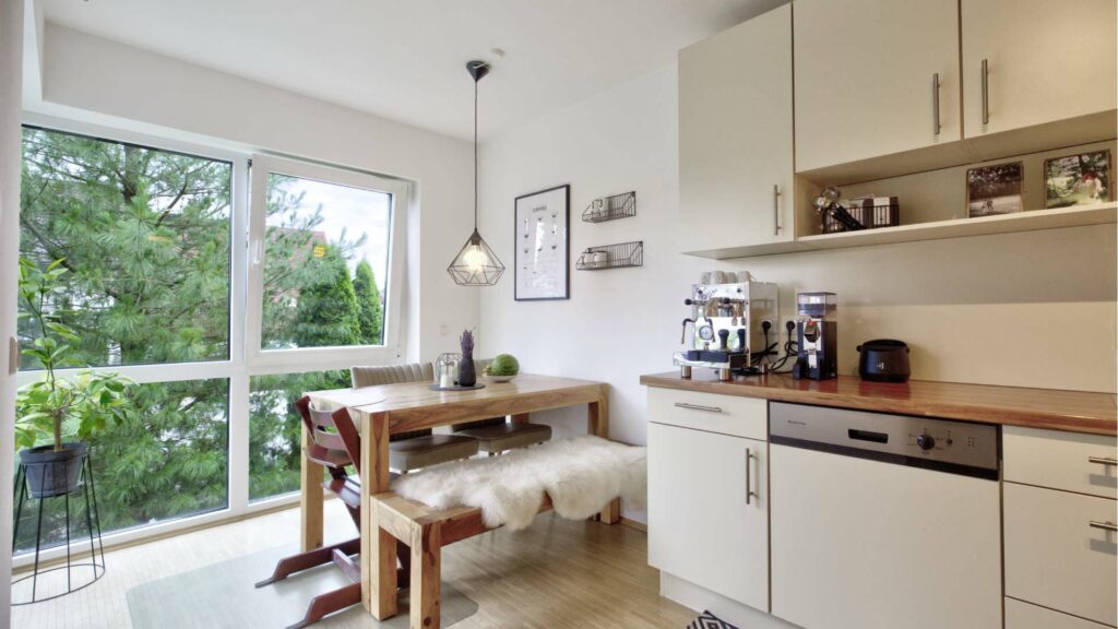Kitchen with a dining area by the window and a green view in an apartment in Munich-Forstenried