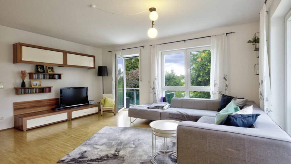 Living room with wall unit, sofa, and balcony access in an apartment in Munich-Forstenried