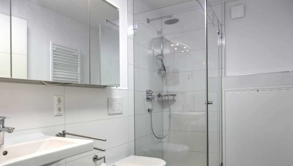 Helles Badezimmer mit Glasdusche, Waschbecken und Spiegelschrank in einer Eigentumswohnung in Gröbenzell