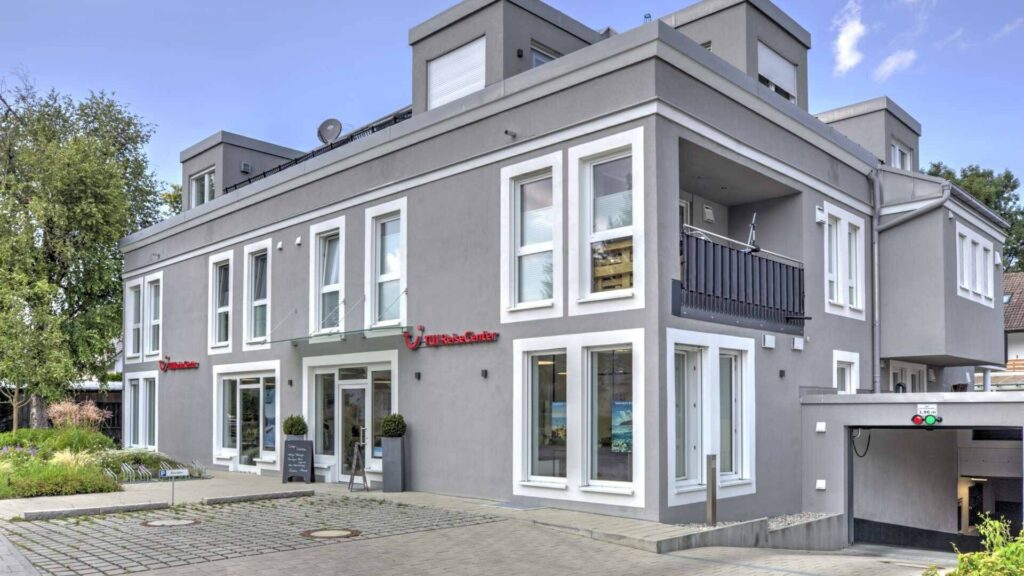 Modernes Wohn- und Geschäftshaus mit grauer Fassade und Ladenlokal im Erdgeschoss in Gröbenzell