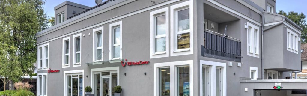Außenansicht eines mehrstöckigen Wohnhauses mit weißer Fassade und Balkonen in Gröbenzell
