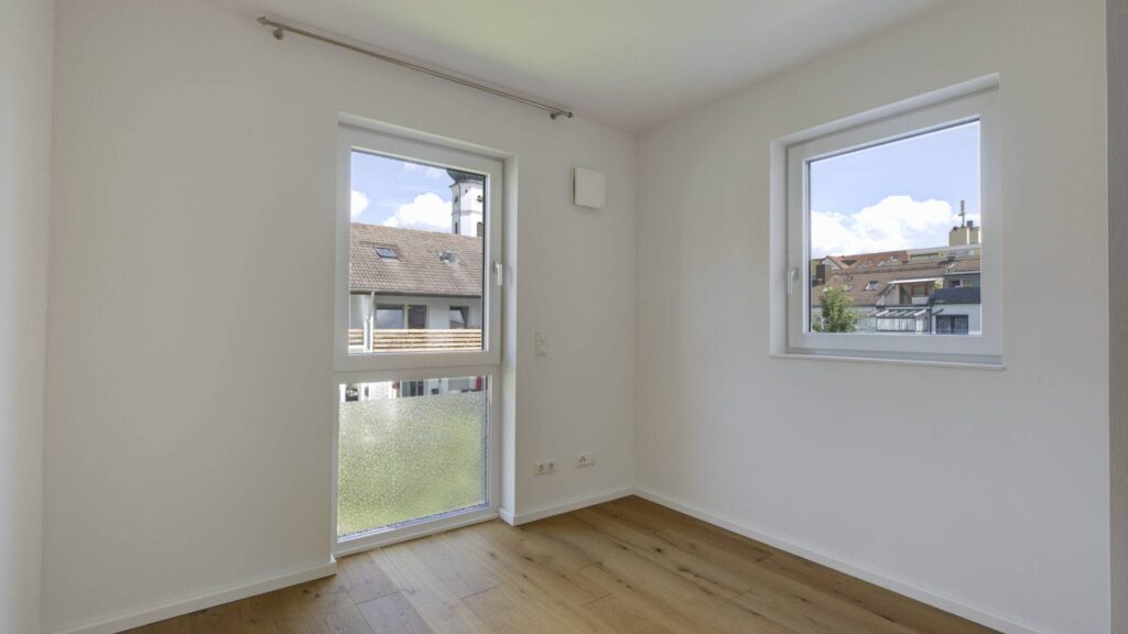 Unmöbliertes Zimmer mit Balkontür, Fenster und hellem Boden in einer Neubauwohnung in Gröbenzell
