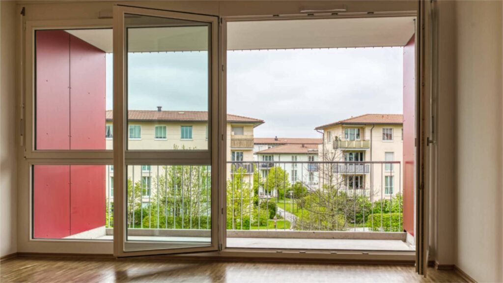 Offene Balkontür vom Wohnzimmer der Großhadener Wohnung mit Blick auf die Wohnanlage