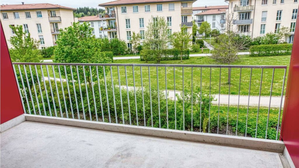 Balkon der Großhadener Wohnung mit Blick auf Grünanlage und Nachbarhäuser im Sommer