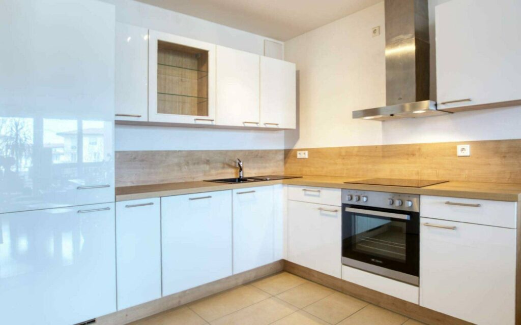Weiße Einbauküche der Großhadener Wohnung mit Kühlschrank und Backofen in Großansicht