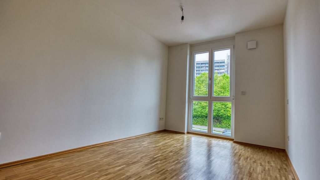 Leeres Schlafzimmer der Großhadener Wohnung mit Parkettboden und Balkontür