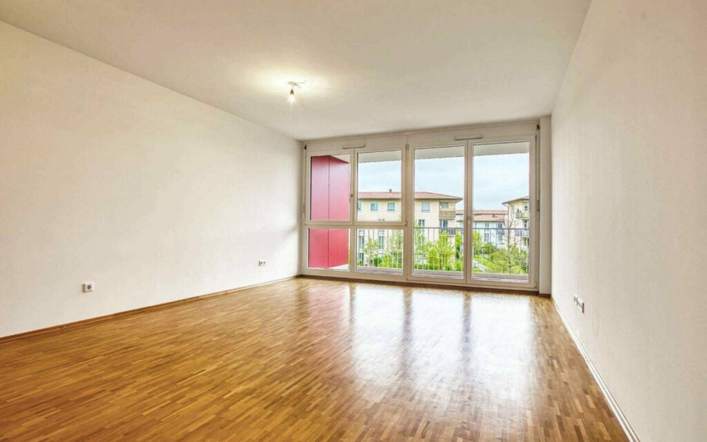 Leeres Wohnzimmer der Großhadener Wohnung mit Parkettboden und Balkontür in Großansicht