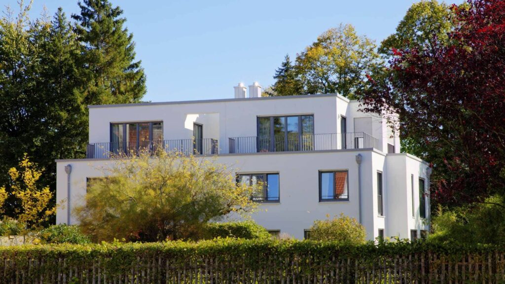 Weiße moderne Villa mit rundem Erker und herbstlichem Garten