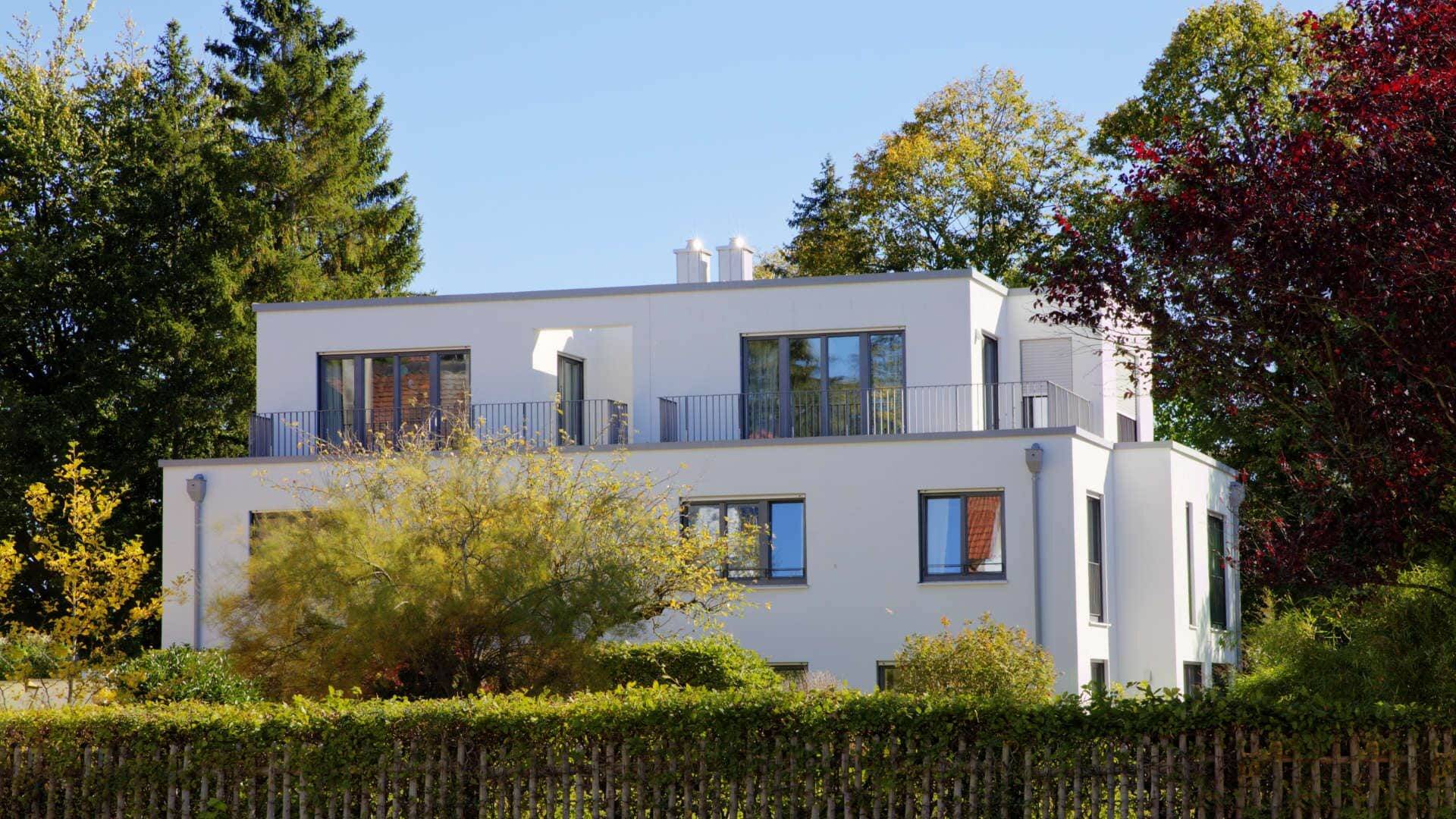 Weiße moderne Villa mit rundem Erker und herbstlichem Garten