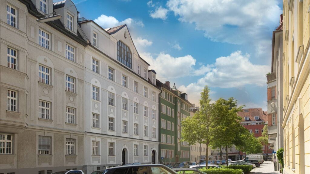 Beige Altbaufassaden mit Gauben entlang einer Münchner Straße mit parkenden Autos – Symbolbild zum Löschen der Grundschuld