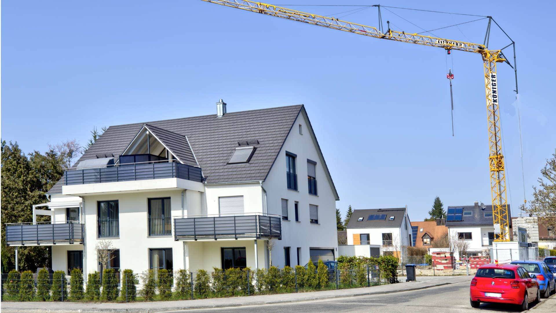 Neu gebautes Wohnhaus mit Balkonen und Baukran im Hintergrund