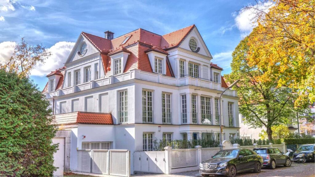 Repräsentative weiße Villa mit rotem Ziegeldach und herbstlich gefärbten Bäumen